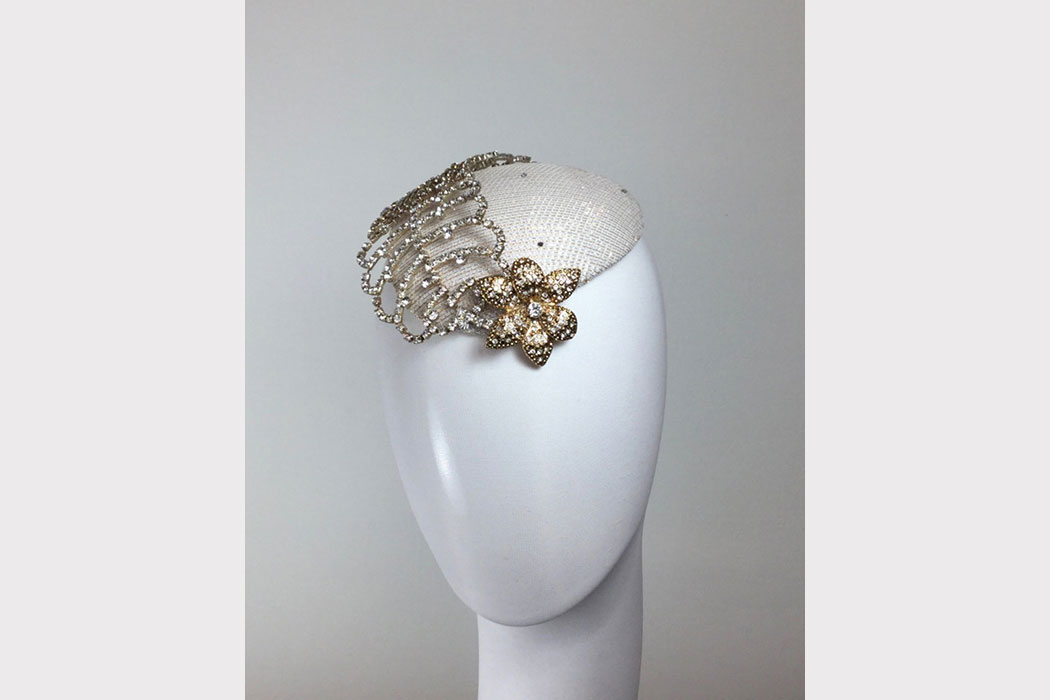 A rhinestone flower with a decorative crystal feather on top of a beret.