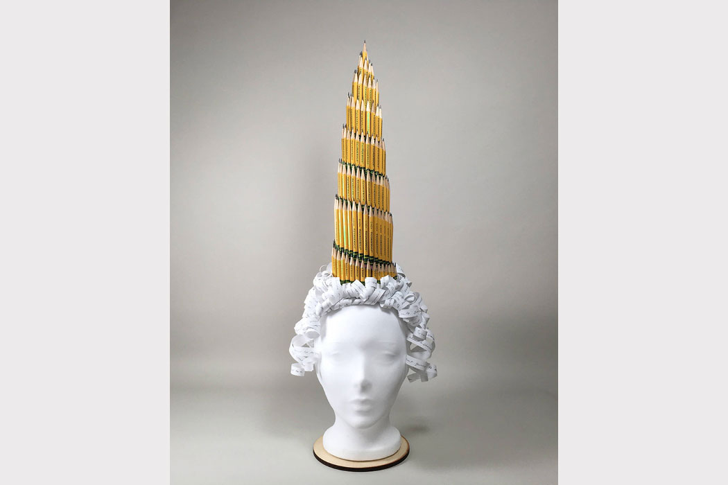 A tall hat made of #2 pencils sitting on top of a curly wig made of paper.